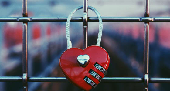 Red heart shaped lock attached to a wire fence