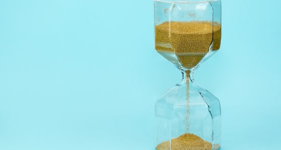 Sandtimer with sand filtering down on a blue background