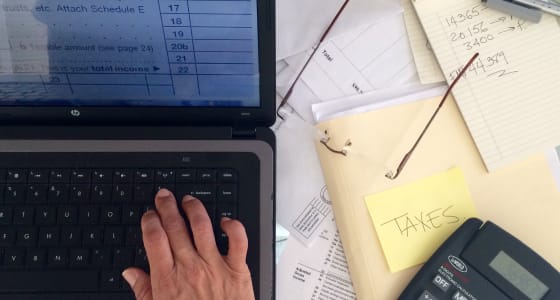 Laptop screen with calculator next to it sitting on top of paperwork