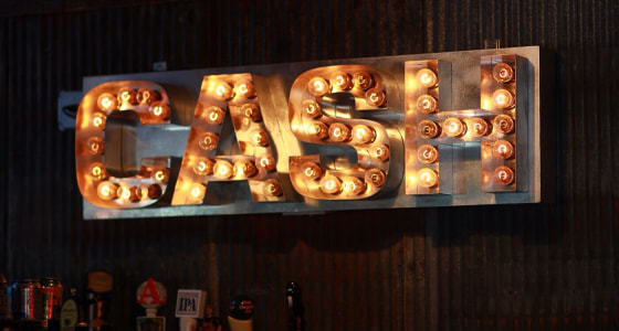 Silver metal bar sign with lighted lettering that reads cash