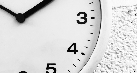 White clock, with black numbers and black hands, on a white wall