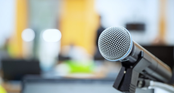 Microphone on a stand on an empty stage in a room with yellow walls