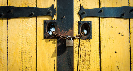 Yellow wooden panelled doors with a locked padlock and chain.