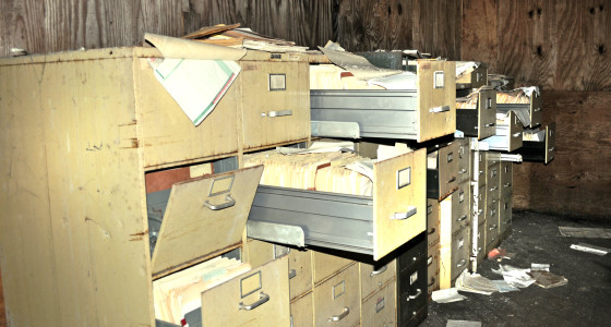 Old filing cabinets with documents strewn in an old disused room