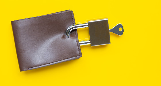 Brown wallet with padlock attached infront of a yellow background