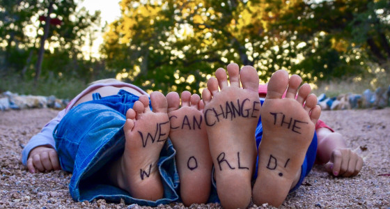 two children pitured lying down with only the soles of their feet in focus which have writing in black pen.