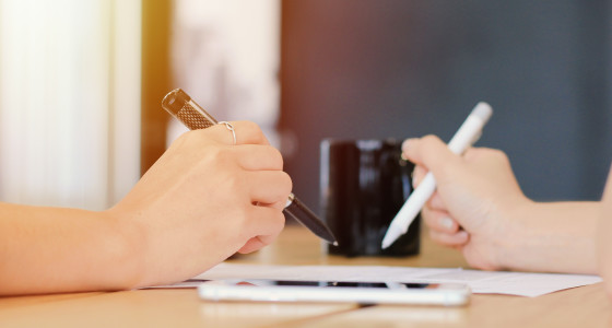 2 people signing a contract with a pen