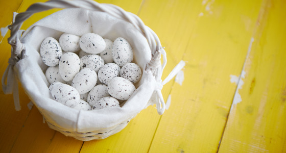 White wicker basket filled with quail eggs.