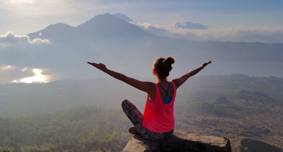 A woman sat high looking upon trees and mountains