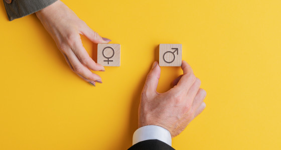 male and female hands holding wooden blocks with gender symbols