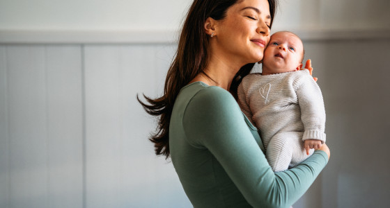 A woman smiling holding a baby.