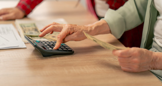 Elderly couple using a calculator and counting money.