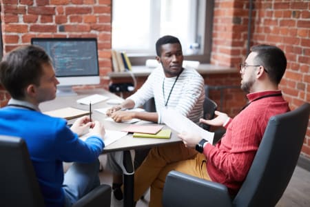 A technology engineers discussing open source software with his two colleagues