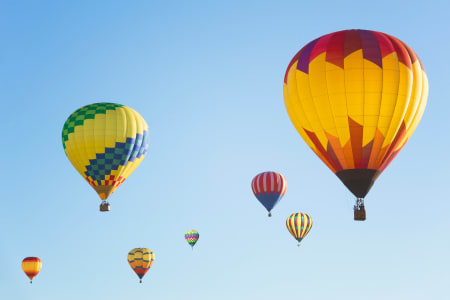 Colourful hot air balloons against blue sky.