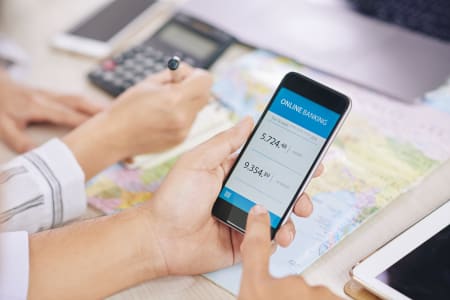 Shot of man with colleague using modern online banking application on smartphone sitting at desk