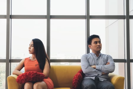 Woman and man look in opposite drections on sofa