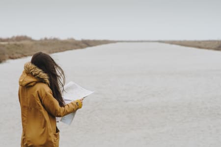 Woman looking at map in front river.