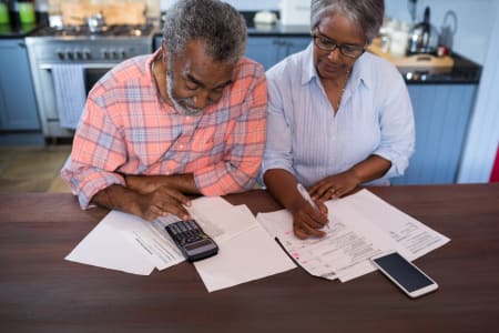 retired couple sit using a calculator