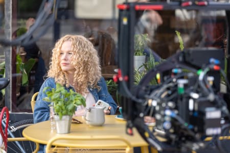 woman sat at cafe surrounded by filming equipment.