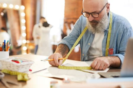 Bearded Tailor holding measuring tape.