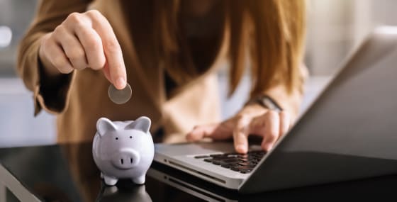 Close up of women saving money into a piggy bank