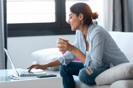 Woman sitting having a coffee with her laptop