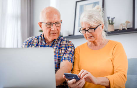 Couple behind computer looking at calculator