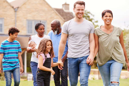 Multi-generational family laughing together whilst going for a walk.