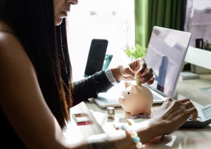 Woman saving money into piggy bank