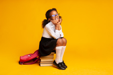 Smiling child sat on a stack of books.