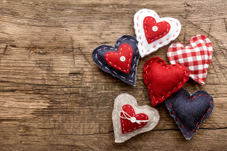 Three patchwork hearts on wooden board.