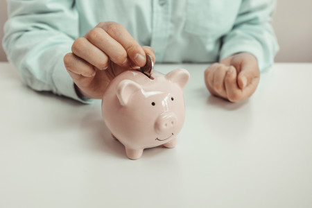 woman putting coin into piggy bank.