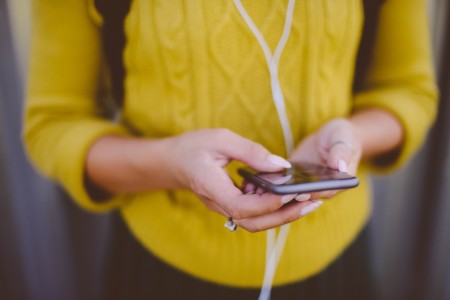 A person wearing a yellow jumper holding a mobile phone