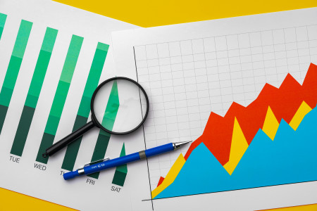 Magnifying glass on top of printed business graphs.