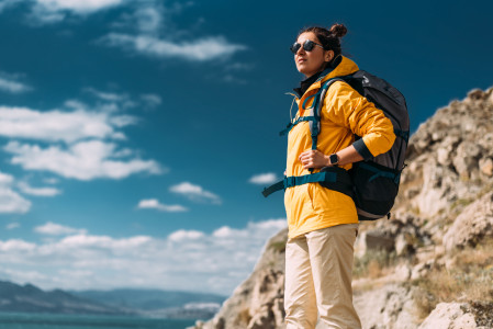 Woman standing, wearing yellow jacket, on top of a hill.