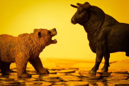 Plastic toy bull and bear, on yellow background.