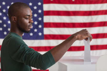 A man casting his vote in front of American flag.