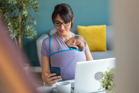 A woman with a baby looking at her phone.