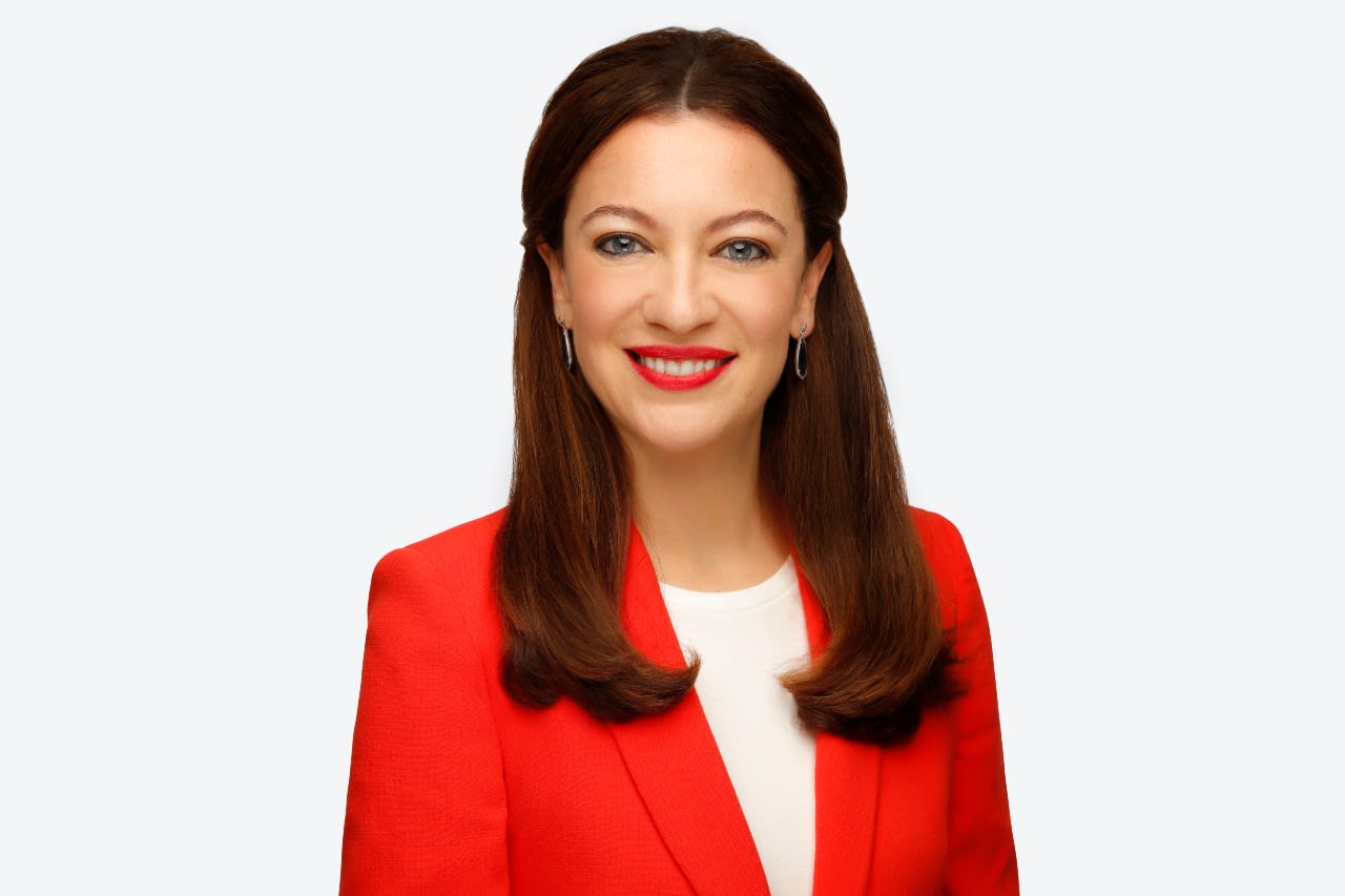 Headshot of Romi, in red dress infront of white background