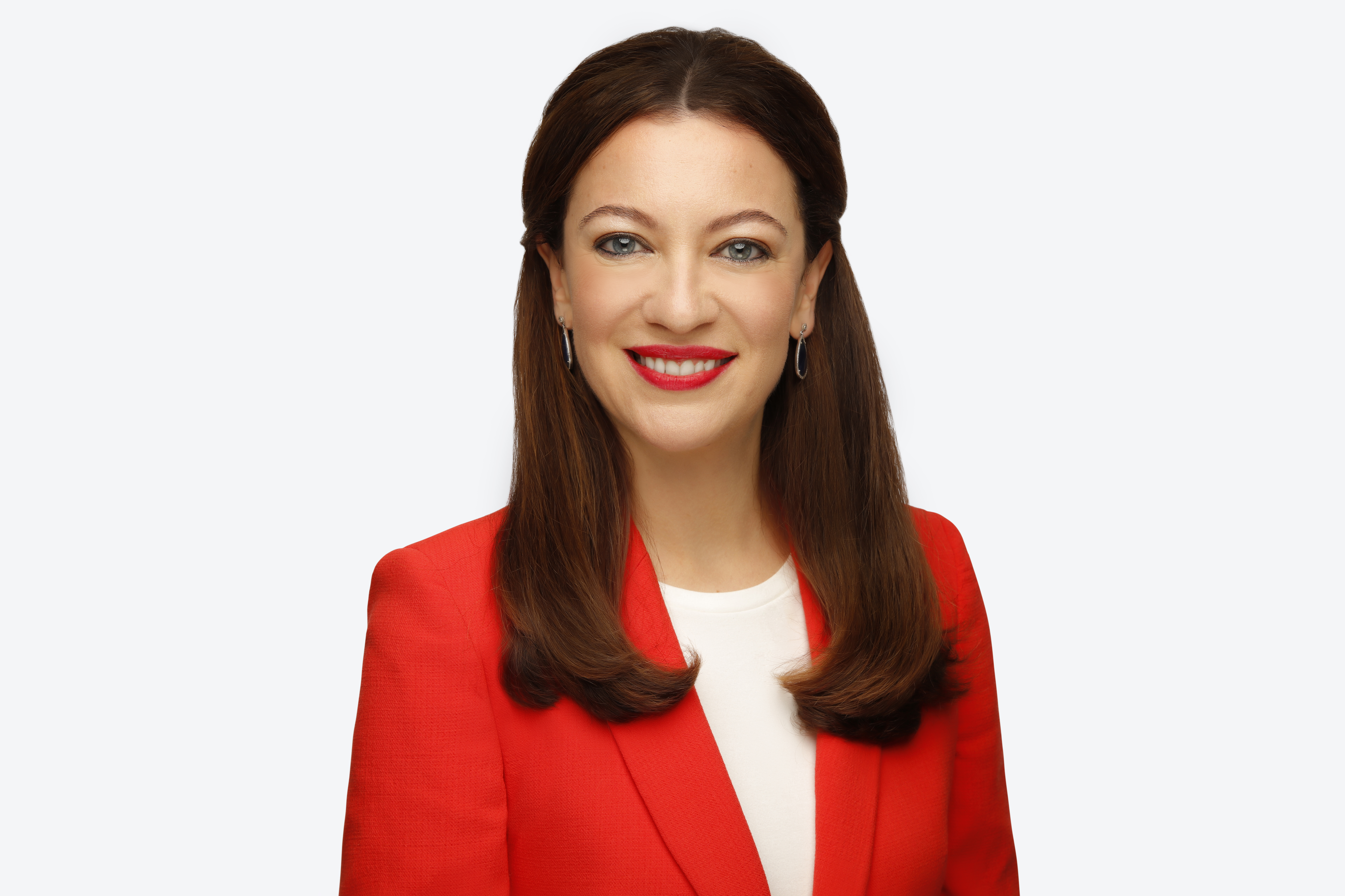 Headshot of Romi, in red dress infront of white background