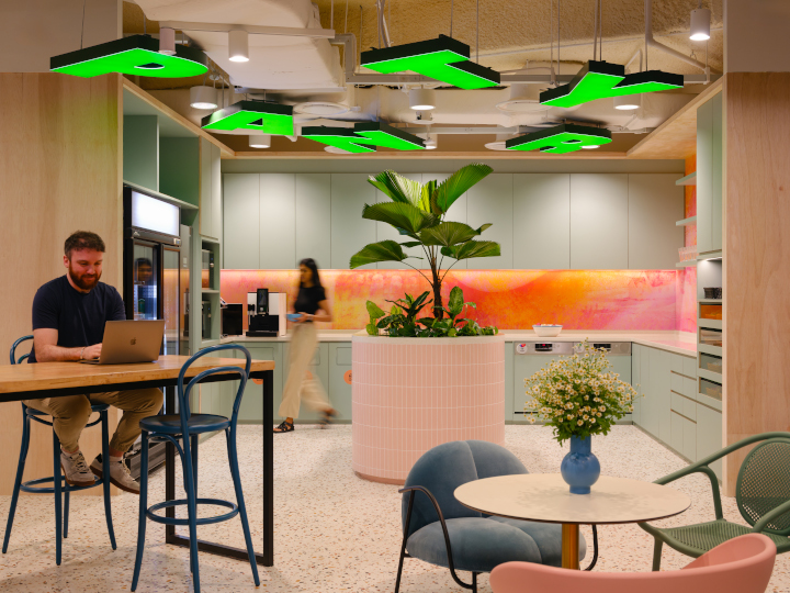 The pantry area at Wise's Singapore office, with a quirky sign hanging from the ceiling and someone working at a table.