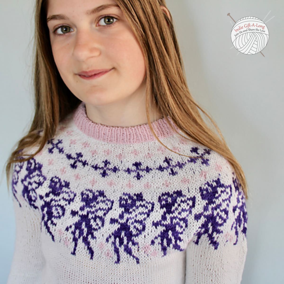 Child wearing white knitted sweater with detailed fairy motifs in the yoke.