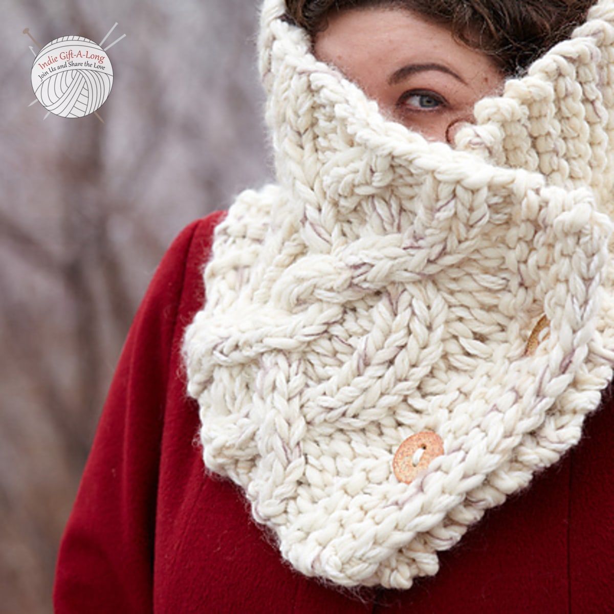 Woman wearing white knitted cowl with large cable motif.