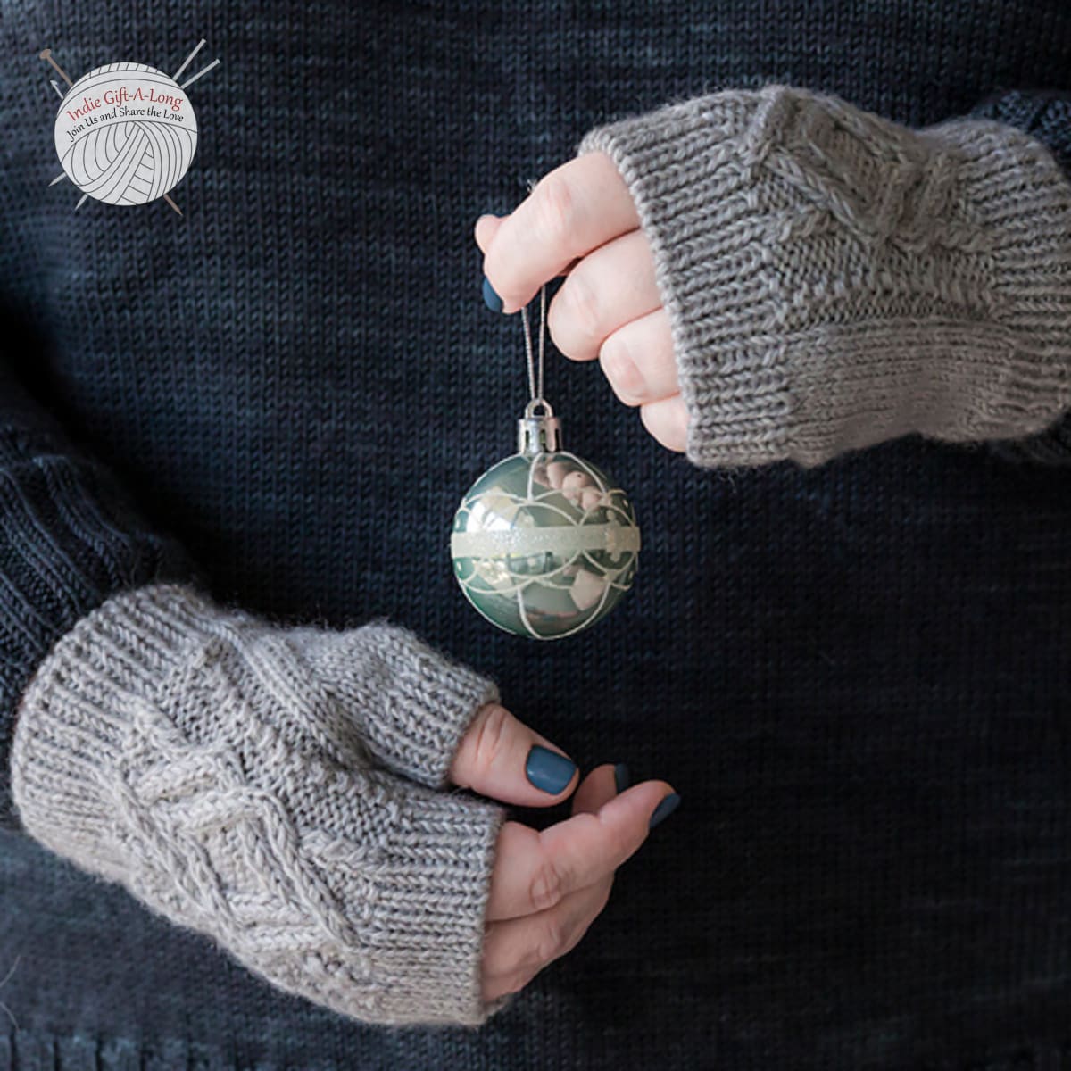 Hands wearing light grey cabled knitted fingerless mitts.