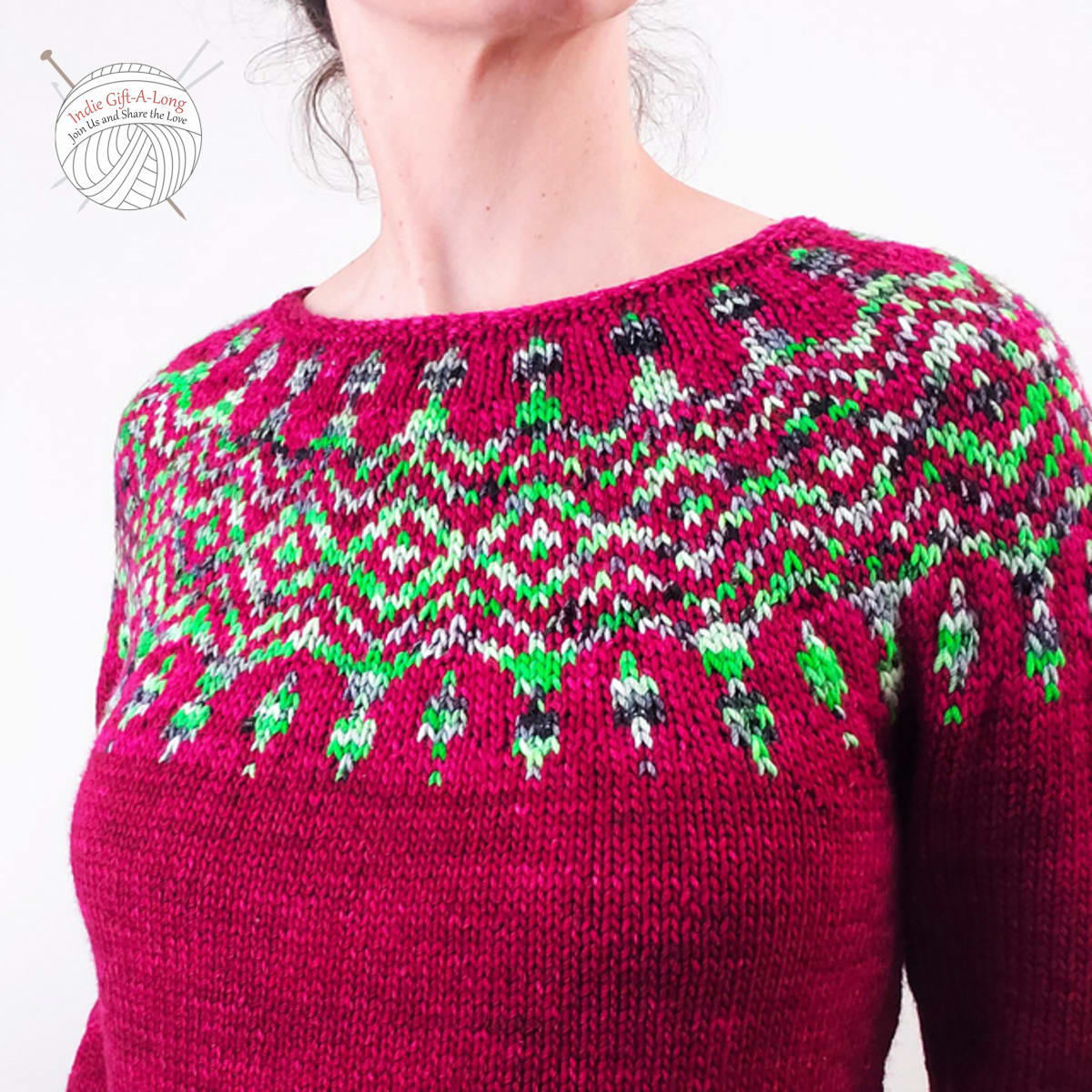 Close up of yoke of red knitted sweater with green and white colourwork motifs.