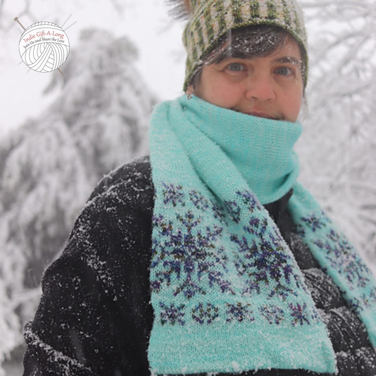 Woman wearing light blue knitted scarf with dark grey snowflake motifs.