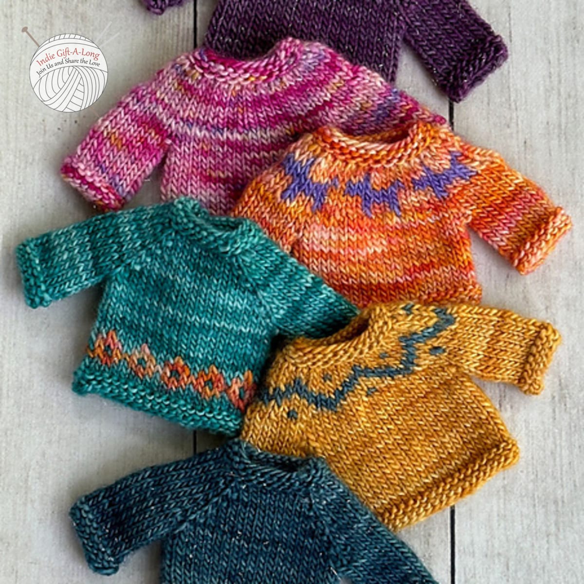 Several tiny knitted sweaters with colourwork motifs.