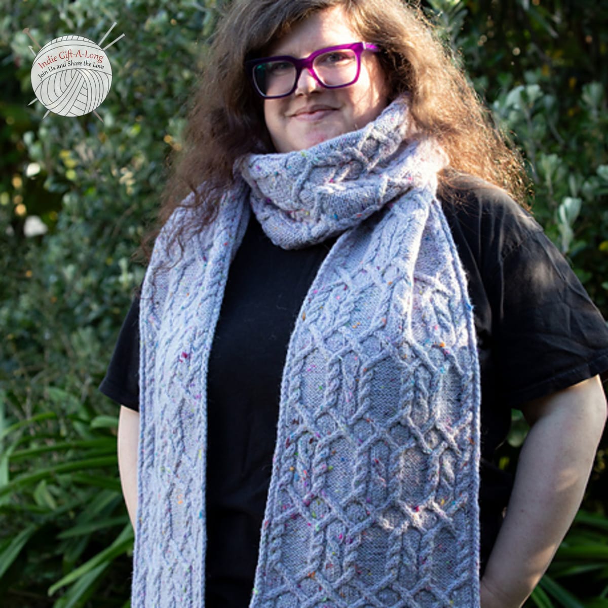 Woman wearing intricately-cabled light blue knitted scarf.