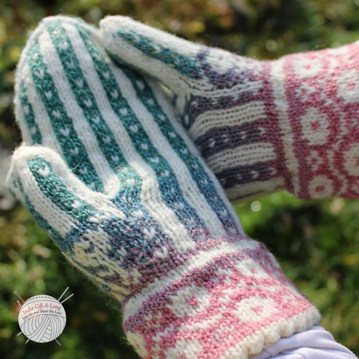 Hands wearing knitted mittens in white and rainbow stranded colourwork with floral motifs on cuff and thumb.