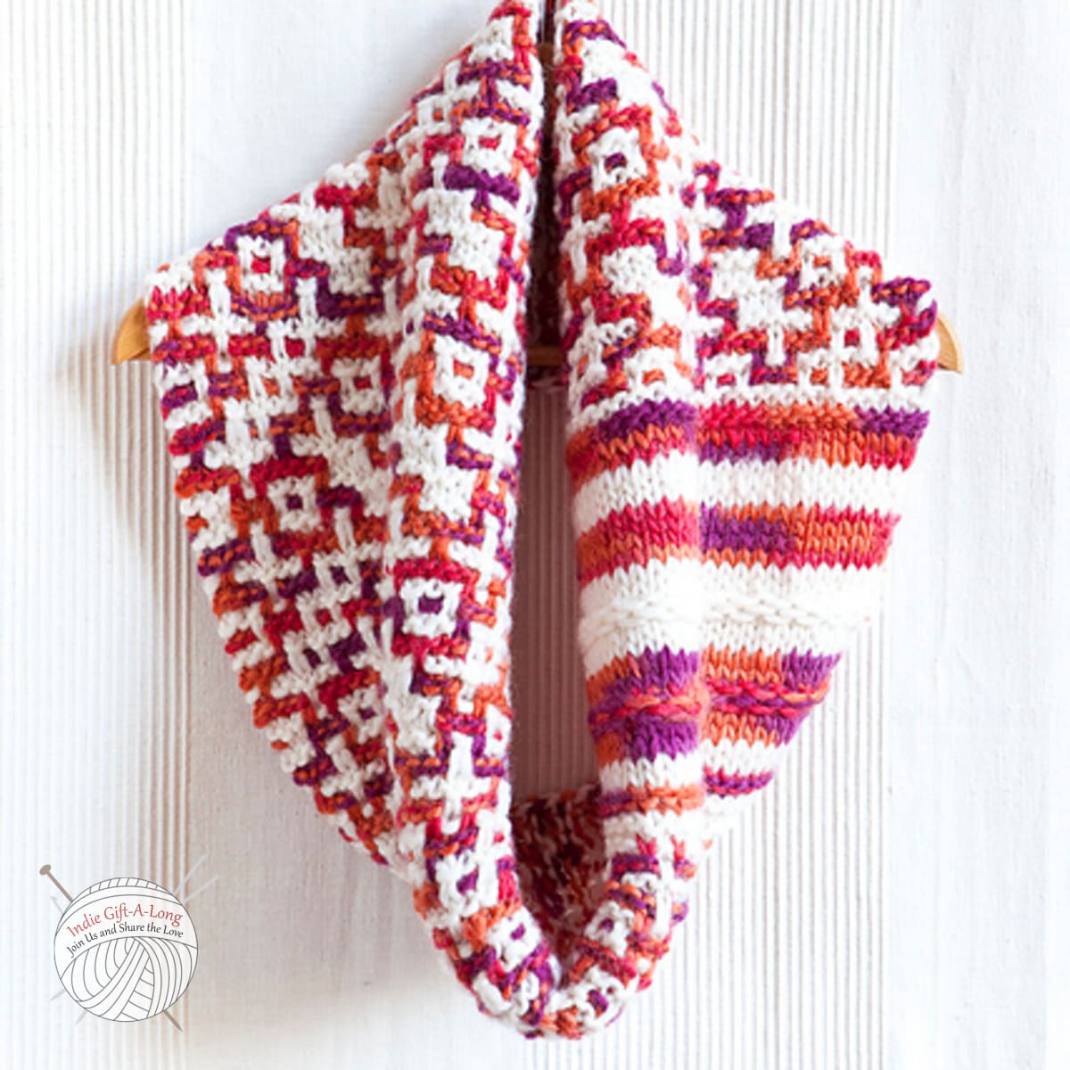 Knitted cowl in white and orange with geometric motif.